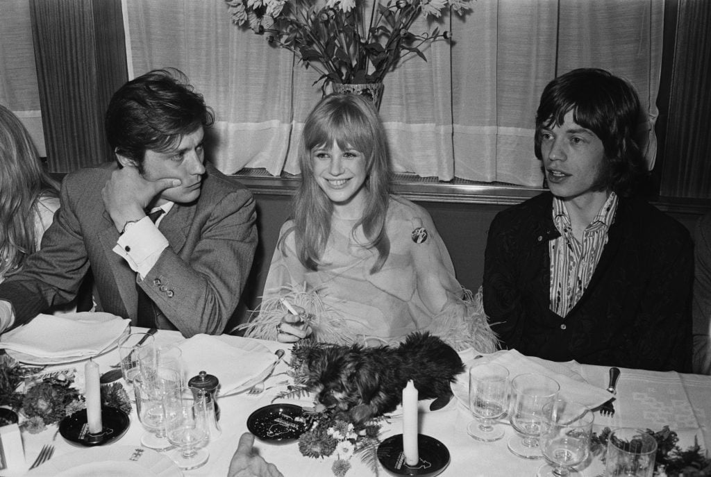 French actor Alain Delon, English singer and actress Marianne Faithfull, and English singer Mick Jagger at a meeting with film director Jack Cardiff to discuss his film 'The Girl on a Motorcycle', 1967.