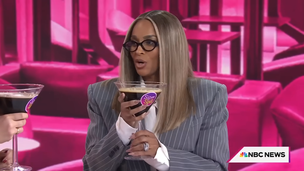 Ciara holds an enormous glass with a dark cocktail within.
