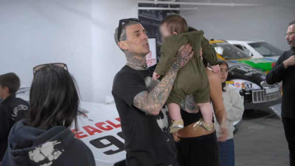 Travis Barker holds son Rocky Barker at the Peterson Automotive Museum in Los Angeles, though Rocky's face is blurred at the time.