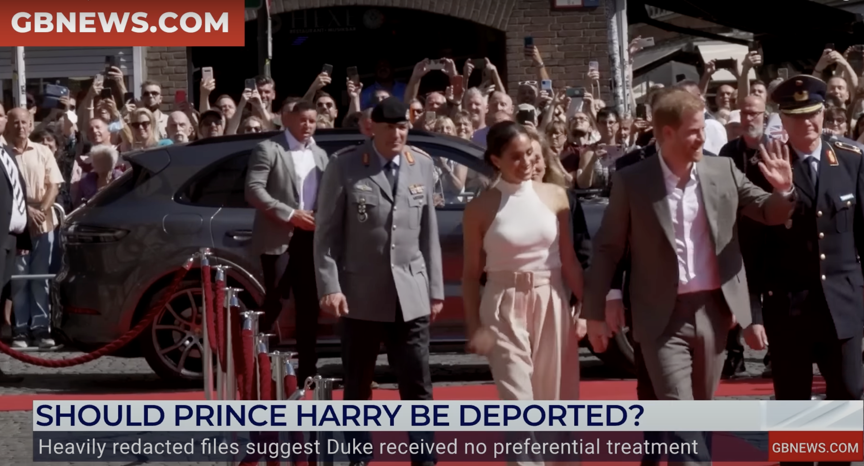 Prince Harry and Meghan Markle greet a crowd of supporters.