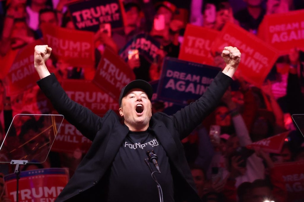 Tesla and X CEO Elon Musk raises his hands as he takes the stage during a campaign rally for Republican presidential nominee, former U.S. President Donald Trump, at Madison Square Garden on October 27, 2024 in New York City.